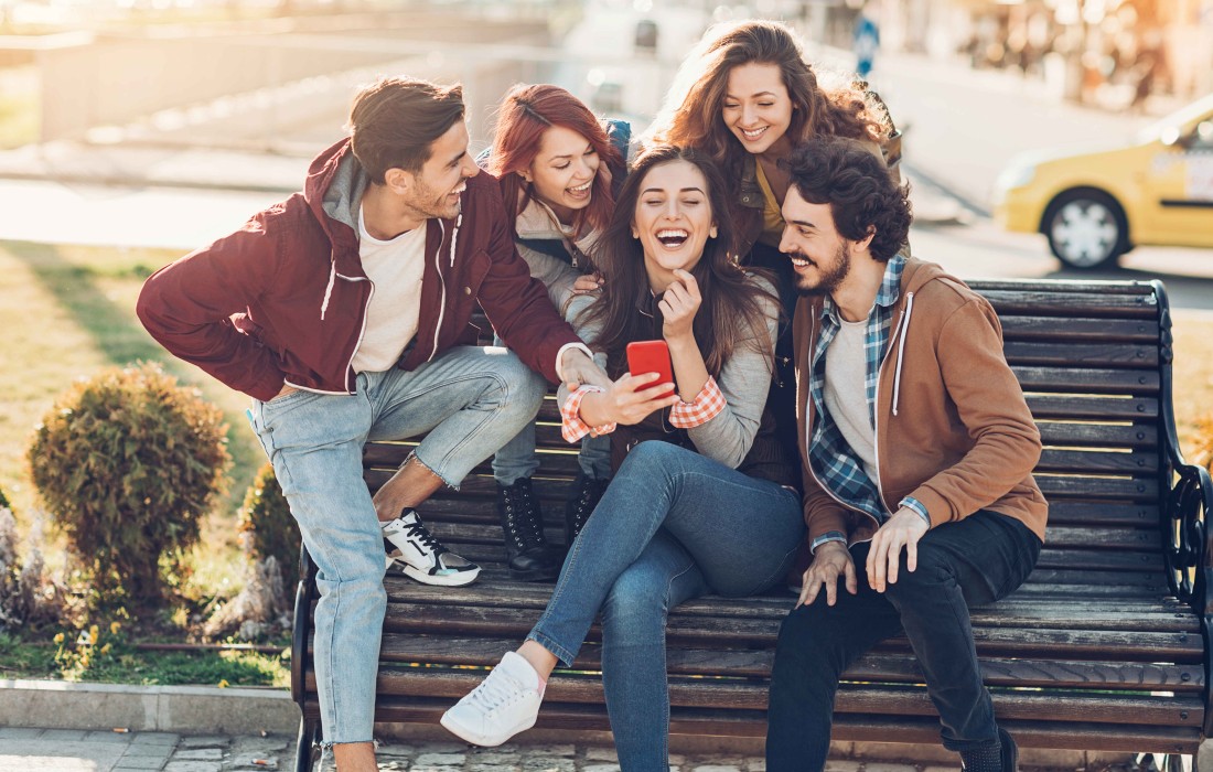 Freundesgruppe sitzt lachend auf Bank